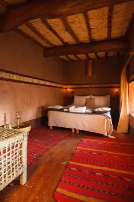 a bedroom with a bed in a room with a rug at Kasbah Tebi in Aït Ben Haddou