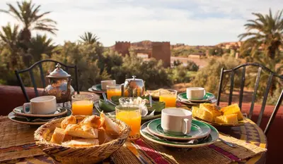 a wooden table with a breakfast of bread and orange juice at Kasbah Tebi in Aït Ben Haddou