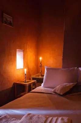 a bedroom with a bed and two tables with lit candles at Kasbah Tebi in Aït Ben Haddou