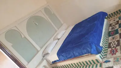 a bed with a blue sheet on top of it at Kasbah Tamariste in Merzouga