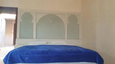 a bedroom with a bed with a blue blanket at Kasbah Tamariste in Merzouga