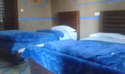 three beds in a room with blue covers on them at Kasbah Tamariste in Merzouga