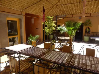 an outdoor patio with tables and chairs and plants at Kasbah La Cigogne in Aït Ben Haddou