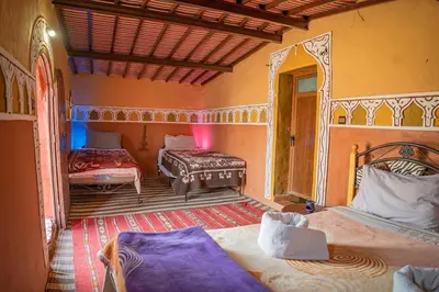 a bedroom with two beds and a table at Sky Luxury Camp in Mhamid