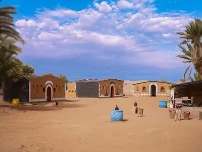a group of buildings in a desert with palm trees at Sky Luxury Camp in Mhamid
