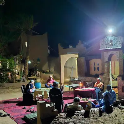 a group of people sitting in a yard at night at Sky Luxury Camp in Mhamid