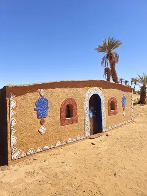 a small building in the desert with a palm tree at Sky Luxury Camp in Mhamid