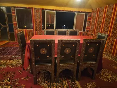 a dining room with a red table and chairs at Typical Luxury Desert Camp in Merzouga