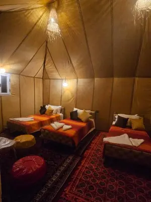 a room with three beds in a tent at Typical Luxury Desert Camp in Merzouga