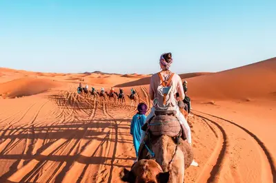 a woman riding a camel in the desert at Typical Luxury Desert Camp in Merzouga
