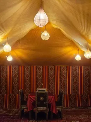 a dining room with a table and two lights at Typical Luxury Desert Camp in Merzouga