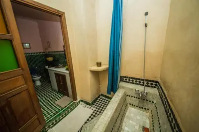 a bathroom with a tub with a shower and a sink at Riad L'Artiste in Fès
