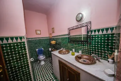 a bathroom with two sinks and a green and white tiles at Riad L'Artiste in Fès