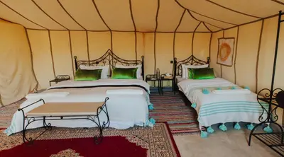 a bedroom with two beds in a tent at Tassili Luxury Desert Camp in Merzouga