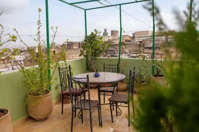 a table and chairs on a balcony with plants at Maison Famille Tazi in Fès