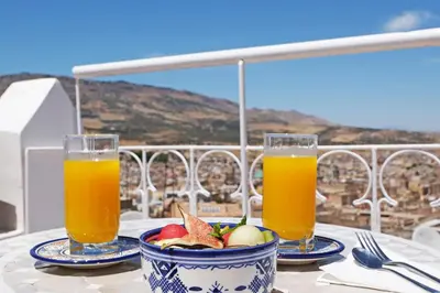 a table with two glasses of orange juice and a bowl of fruit at Riad Alassala Fes in Fès