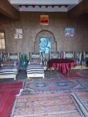 a living room with couches and a table and a rug at Auberge L'Oasis in Foum Zguid