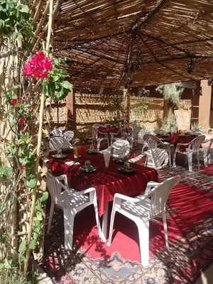 a table with a red table cloth and white chairs at Auberge L'Oasis in Foum Zguid