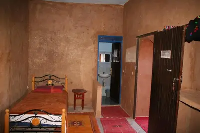 a small bedroom with a bed and a bathroom at Auberge L'Oasis in Foum Zguid