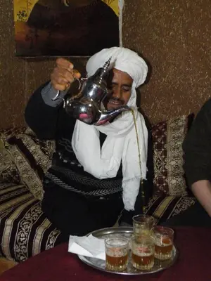 a man sitting on a couch holding a pot at Auberge L'Oasis in Foum Zguid