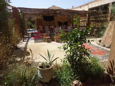 a patio with a table and chairs in a yard at Auberge L'Oasis in Foum Zguid