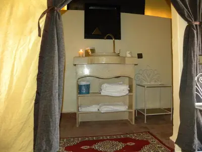 a living room with a fireplace and a tv at Sahara Luxury Camp in Zagora