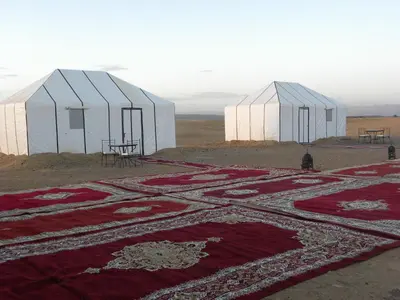 two large white domes with red carpets on a field at Sahara Luxury Camp in Zagora