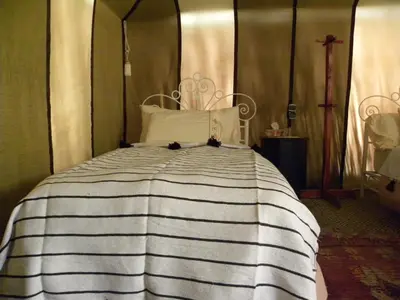 a bed with a black and white striped comforter at Sahara Luxury Camp in Zagora