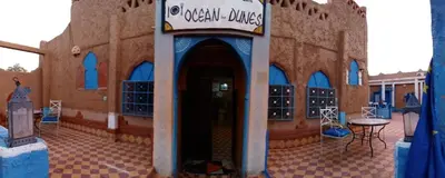 a building with a sign that reads urgent drugs at Auberge Camping Ocean des dunes in Merzouga