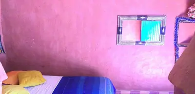 a room with a pink wall with a bed and a mirror at Auberge Camping Ocean des dunes in Merzouga