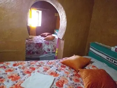 a bedroom with two beds and a mirror at Auberge Camping Ocean des dunes in Merzouga