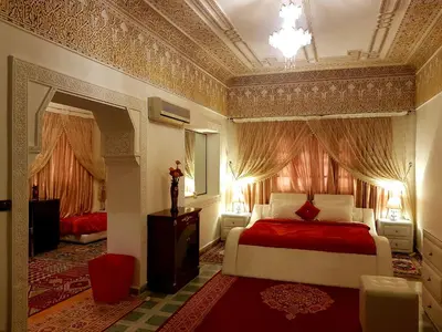 a bedroom with a bed with red sheets and a ceiling at Riad Jasmine Sud in Zagora