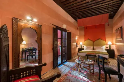 a bedroom with a bed and a table and a mirror at Algilà Fes Riad Medina Charme Hotel in Fès