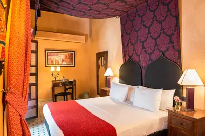 a hotel room with a bed with a red and white bedspread at Algilà Fes Riad Medina Charme Hotel in Fès
