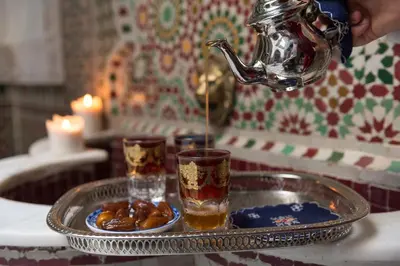 a teapot pouring tea into a tray with a plate of food at Algilà Fes Riad Medina Charme Hotel in Fès