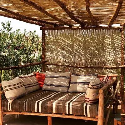 a wooden bench sitting under a pergola with pillows at Les Jardins de Taja in Ourika