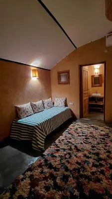 a bedroom with a large bed with a rug at Les Jardins de Taja in Ourika