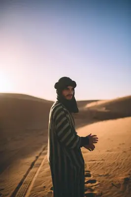 a man standing in the sand in the desert at Dunes Luxury Camp in Merzouga