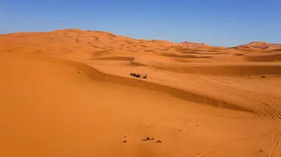 a group of people walking in the desert at Dunes Luxury Camp in Merzouga