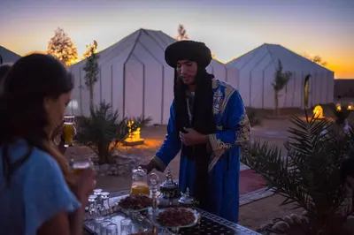 a man standing in front of a table with food at Dunes Luxury Camp in Merzouga
