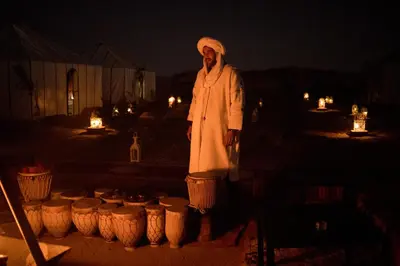 a man standing in front of a row of lights at Dunes Luxury Camp in Merzouga