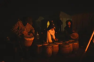 a group of people standing around a table in the dark at Dunes Luxury Camp in Merzouga