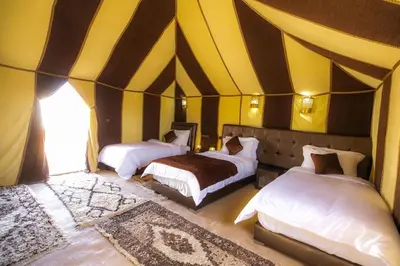a bedroom with two beds in a tent at Dunes Luxury Camp in Merzouga