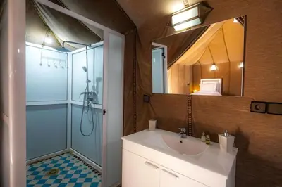 a bathroom with a sink and a shower and a mirror at Dunes Luxury Camp in Merzouga