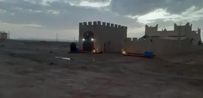 a castle in the middle of a desert with lights at Maison Riad Tamarighte in Merzouga