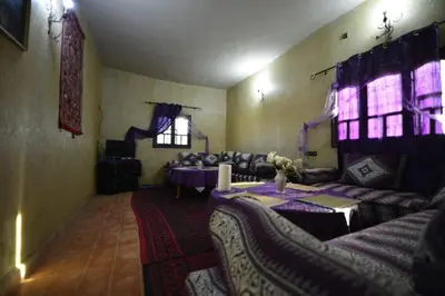 a living room with couches and a table in a room at Maison Riad Tamarighte in Merzouga