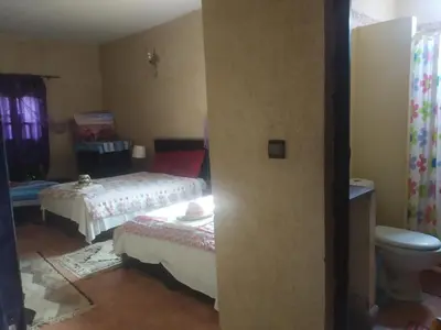 a small bedroom with two beds and a toilet at Maison Riad Tamarighte in Merzouga
