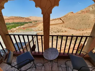 a balcony with chairs and a view of the desert at Kasbah Chems in Kalaat MGouna