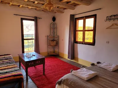 a room with two beds and a table and windows at Kasbah Chems in Kalaat MGouna