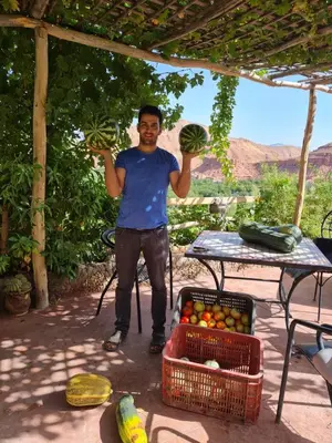 a man is holding up two baskets of fruit at Kasbah Chems in Kalaat MGouna